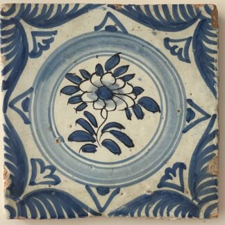 Marseille Clerissy faience tile, circa 1700, with a blue floral medallion, manganese outlines and palmette borders, showing edge chips.