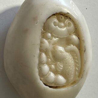 Oval creamy white stone sculpture with a carp carved in a recessed relief panel